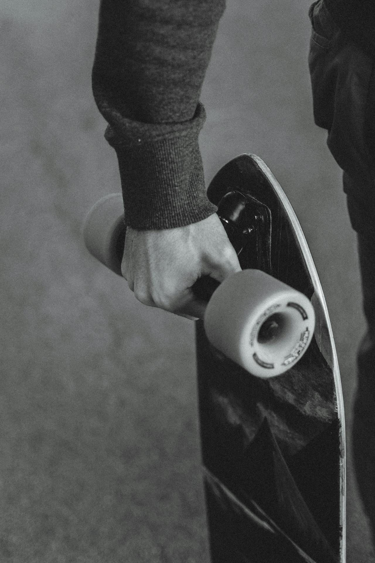 Crop man with skateboard on road